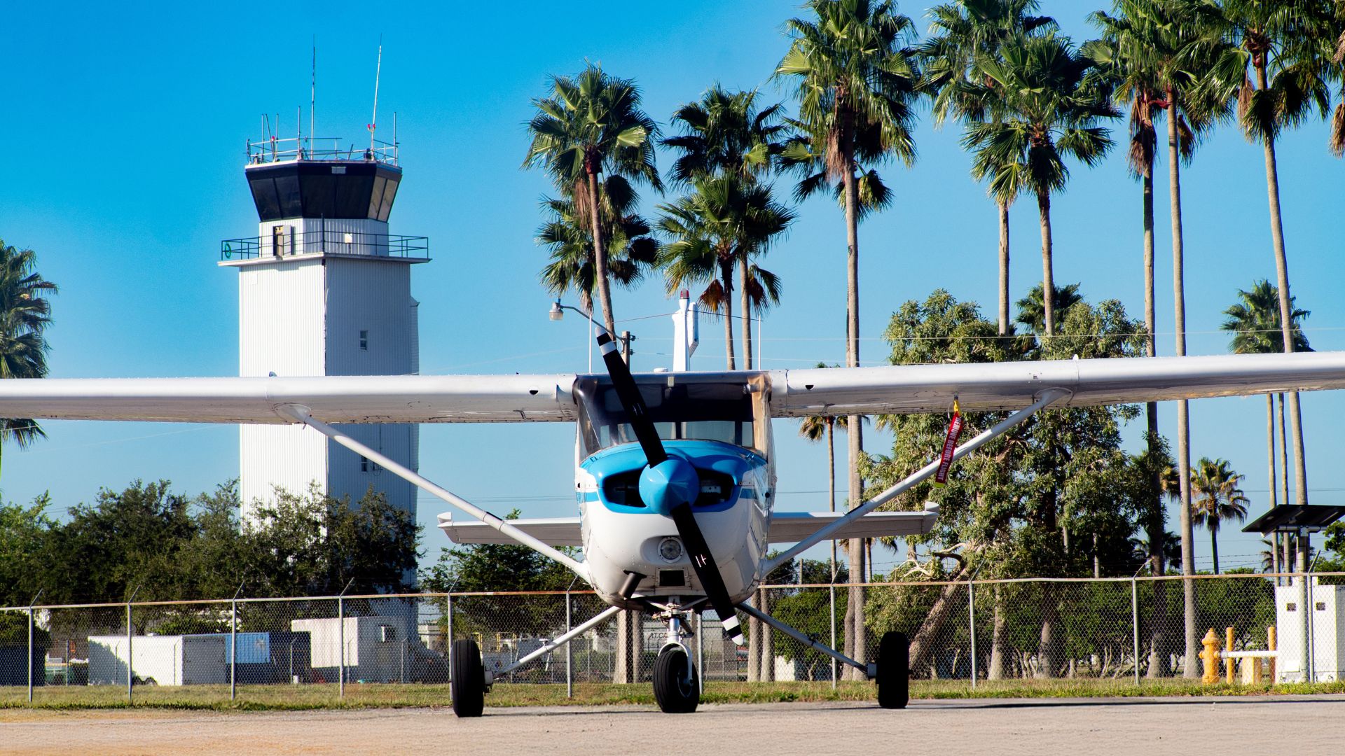 Training aircraft parked near the airport tower and palm trees